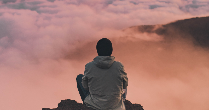 Un homme sur le sommet d'une montagne qui observe l'horizon et profite de l'instant présent