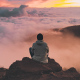 Un homme sur le sommet d'une montagne qui observe l'horizon et profite de l'instant présent