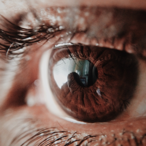 vue un oeil marron dans lequel on voit en reflet le visage d'une autre personne